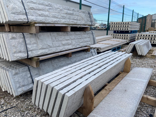 Stacked concrete gravel boards stored outdoors, intended for landscaping or construction purposes.